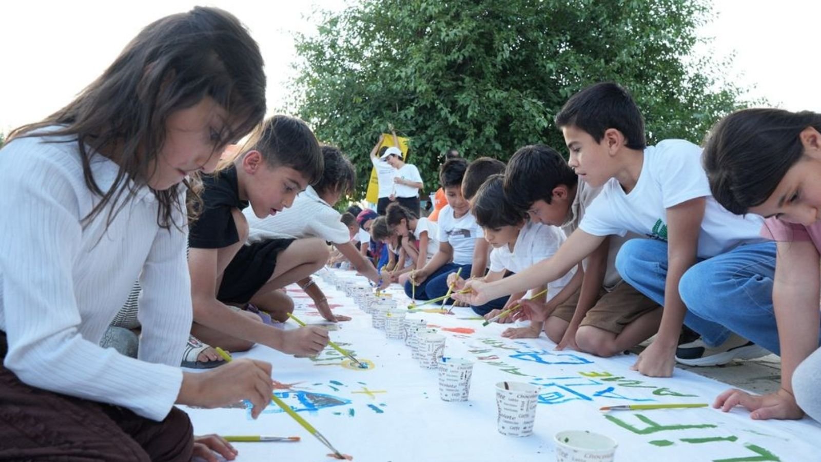 Kırsal mahallede ritim çubukları ve boyalarla çalışan çocuklar