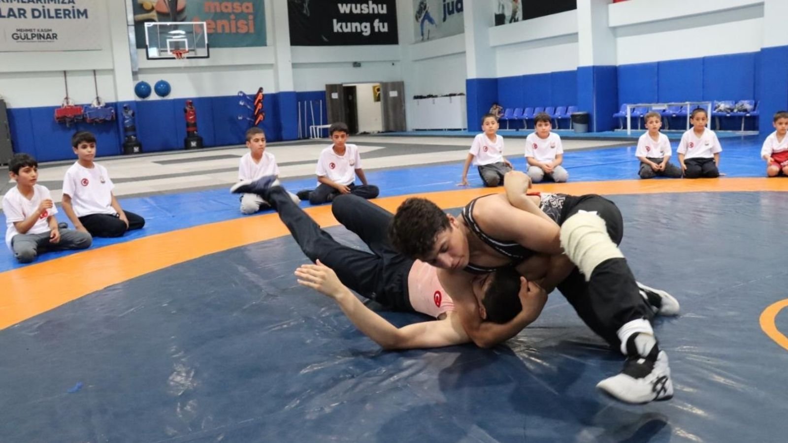 Paşabağı Spor Salonu’nda antrenör eşliğinde güreş çalışan çocuklar